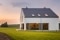 La imagen muestra una casa con un jardín verde y una puesta de sol de fondo.
