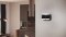 La imagen muestra el cronotermostato Carrier Comfort Management T300 en la pared de un salón moderno.
